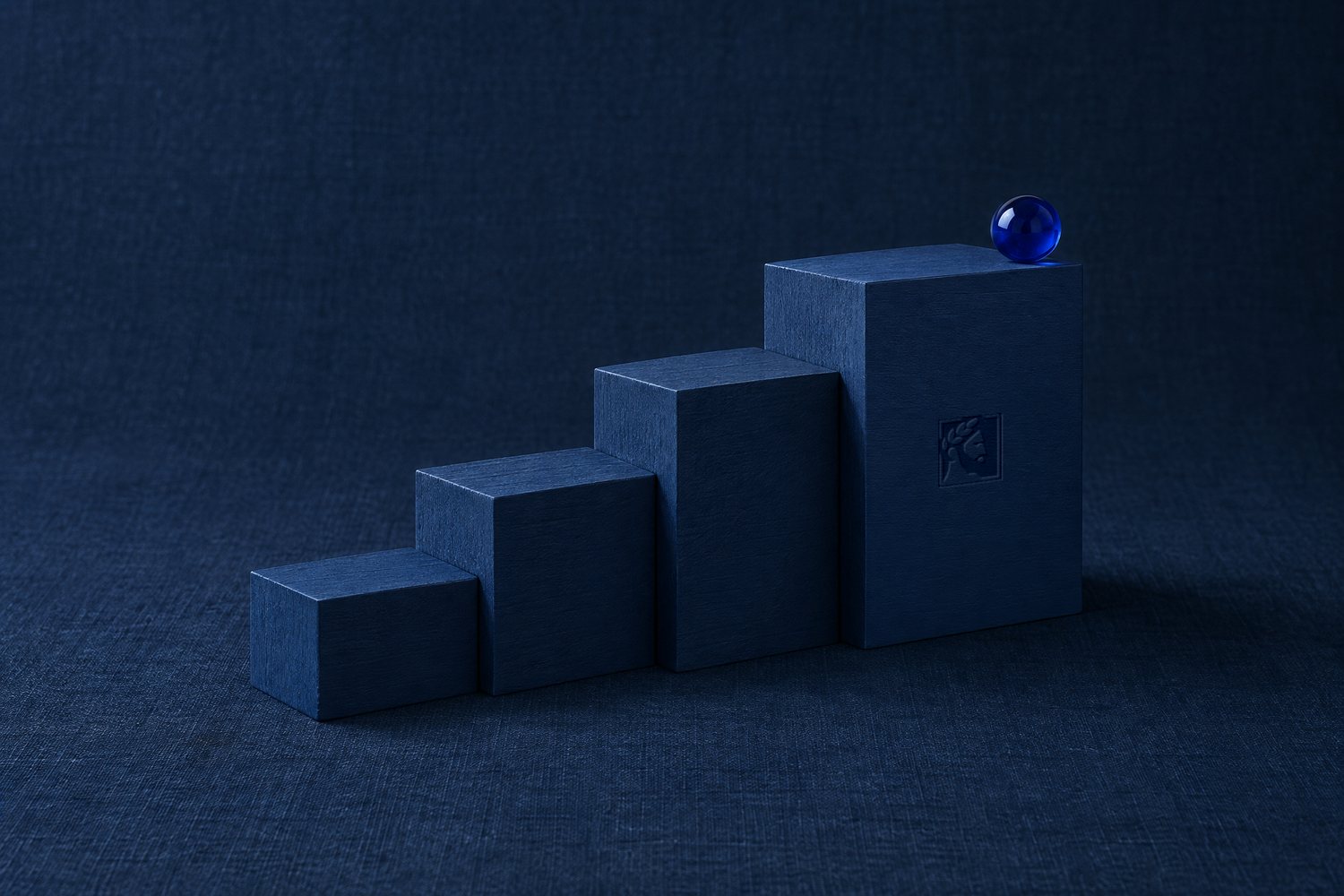 Four navy blocks rising as steps, the tallest pressed with the Olivent mark, a cobalt marble on top