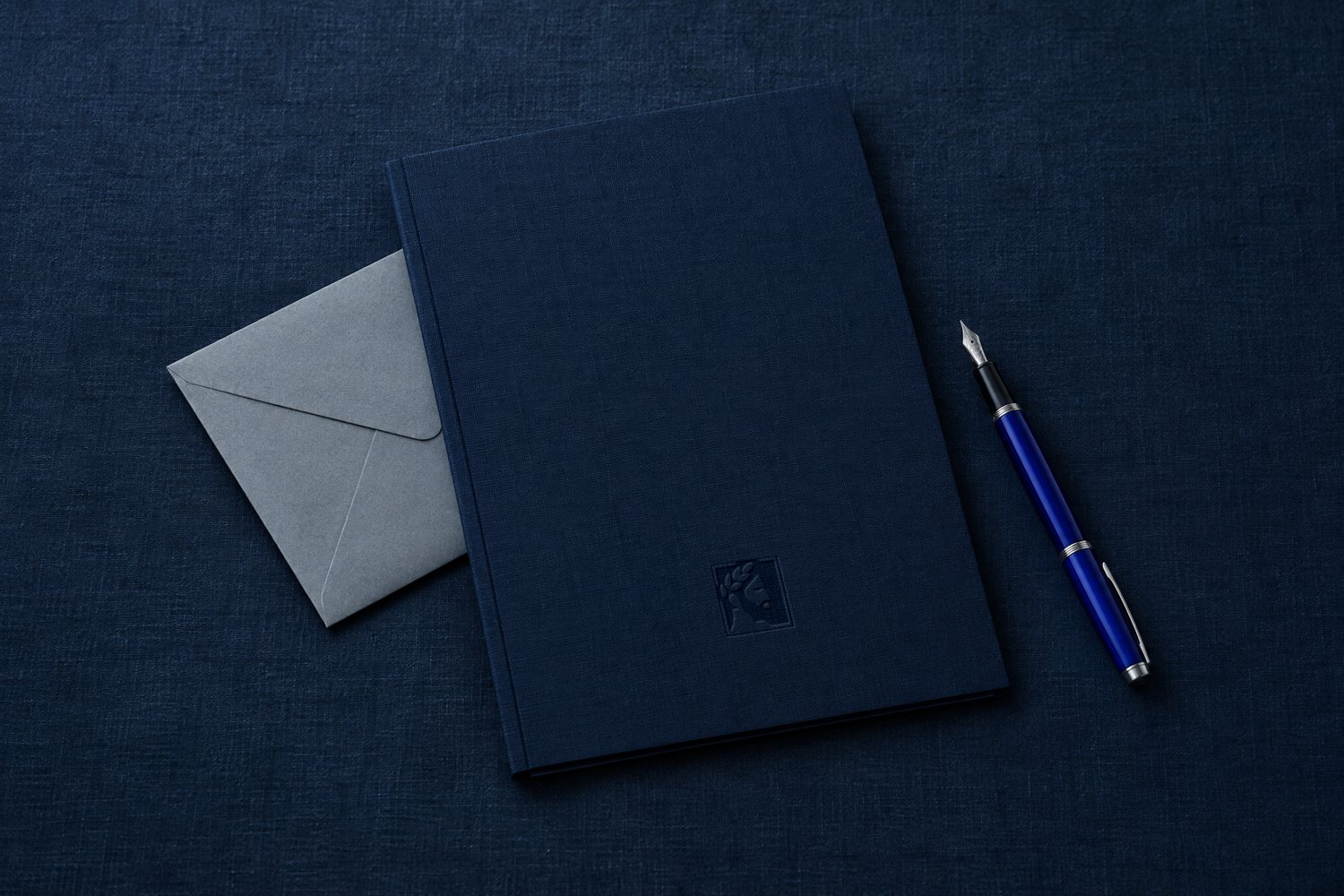A navy cloth folder debossed with the Olivent mark, a grey envelope and a cobalt fountain pen
